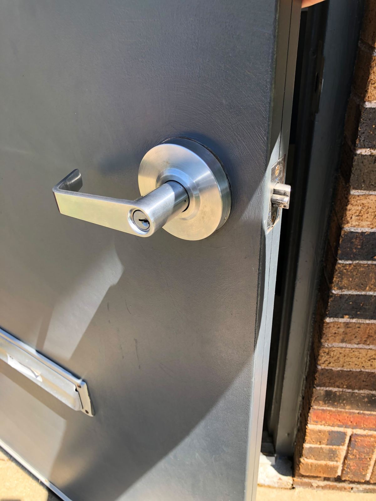 Brushed stainless commercial lever lock on a gray metal door